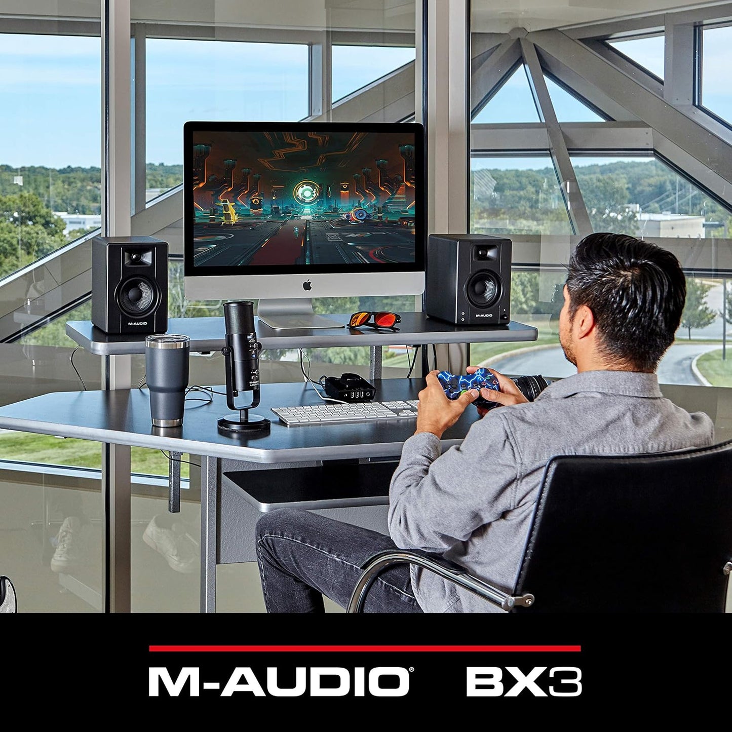 M-Audio BX3 3.5 studio monitors on a modern desk with a computer and microphone setup